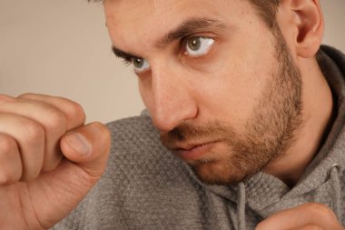 Spor kapüşonlu bir adam yumruklarını sıkmış, harekete hazır bir şekilde duruyor. Onun duruşu bir boksörünkine benziyor, enerji ve güven saçıyor. Ortam dinamik ve yoğun.