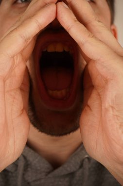 Koyu renk saçlı adam iki avucunu da ağzının etrafında tutarak derme çatma bir megafon oluşturuyor. Animasyon jesti bağırmayı ya da önemli bir şeyi duyurmayı gerektiriyor. İfadesi aciliyet saçıyor.