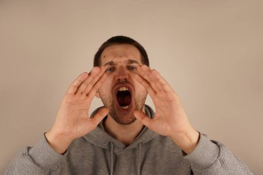 Koyu renk saçlı adam iki avucunu da ağzının etrafında tutarak derme çatma bir megafon oluşturuyor. Animasyon jesti bağırmayı ya da önemli bir şeyi duyurmayı gerektiriyor. İfadesi aciliyet saçıyor.