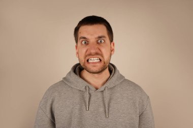 Yüzü yoğun bir öfkeyle çevrili, ağzı sonuna kadar açık, saf duygularını gösteren bir adam. Onun ifadesi güçlü bir hayal kırıklığı ve öfke taşır. Görüntü onun duygusal patlamasının gücünü yakalıyor.