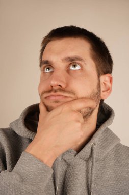 Eli çenesinde, adam derin düşüncelere dalmış. Bakışı ve ifadesi odaklandığını ve tefekkür ettiğini gösteriyor. Bu poz ciddiyet ve yansıma hissi uyandırıyor.
