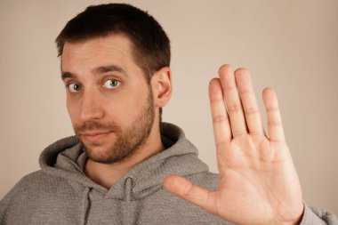 Bir adam dostça selamlaşmak ya da veda etmek için elini kaldırır. Onun sıcak ifadesi hoş geldin jestini artırır. Sahne pozitifliği ve ulaşılabilirliği ifade eder