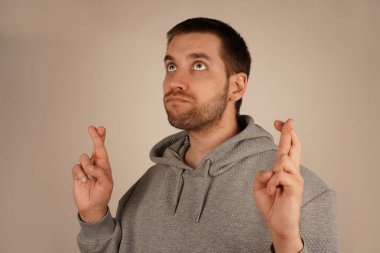 İki eli çapraz olan adam, şans diliyor. Rahatlamış tavrı bu sembolik jestin çekiciliğini vurguluyor. Sahne iyimserlik ve iyi niyetle parlıyor.