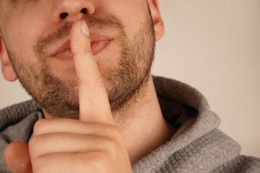 İşaret parmağıyla dudaklarına bastırılan adam sakin bir şekilde sessizlik talep ediyor. Onun bileşik ifadesi jestin etkinliğini artırır. Görüntü, sükunet ve düzeni sağlar.