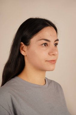 Kadının yüzü yakın plan çekimde, rahatlatıcı bir rahatlama ve dinginlik yayıyor. Duruşu sıradan ve zahmetsiz bir havayı yansıtıyor. Bir anlık doğal güzellik ve kendine güven.