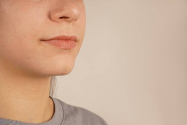 Kadın yüzünün bir parçası. Genç bir kızın çenesinin yakın çekimi. Çenenin, dudakların ve burnun detaylı tasviri. Güzel bir insanın zarif yüz hatları.