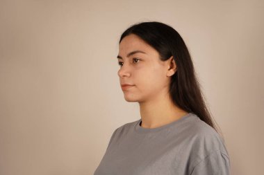 Kadının yüzü yakın plan çekimde, rahatlatıcı bir rahatlama ve dinginlik yayıyor. Duruşu sıradan ve zahmetsiz bir havayı yansıtıyor. Bir anlık doğal güzellik ve kendine güven.