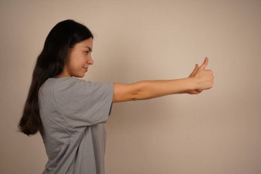 İki eliyle de baş parmağını kaldıran kadın, güçlü bir şekilde onaylıyor. Onun coşkulu duruşu ve parlak enerjisi benzer şekilde yayıldı. Sıcak ve neşelendirici bir pozitiflik anı