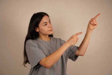 Genç kadın iki işaret parmağıyla tek bir yönü işaret ediyor. Bu da yolu gösteriyor. Duruşu özgüvenli ve anlamlı. Amaç ve berraklıkla dolu bir jest.