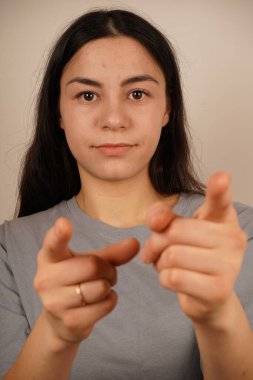 Genç kadın iki işaret parmağıyla tek bir yönü işaret ediyor. Bu da yolu gösteriyor. Duruşu özgüvenli ve anlamlı. Amaç ve berraklıkla dolu bir jest.