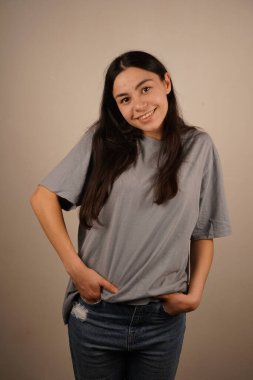 Genç bir kadın uzun siyah saçlarıyla rahat bir poz verir. Elleri rahat bir şekilde kotunun cebine yerleştiriliyor. Kolay bir özgüveni simgeliyor. Onun ifadesi bir tefekkür.