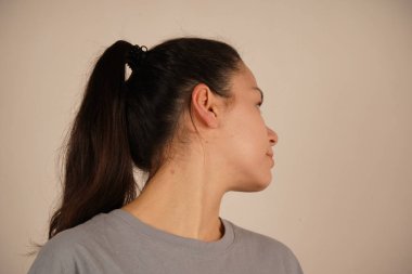 Genç bir kadının yan profili uzun saçlarını at kuyruğu şeklinde gösteriyor. Yüzünün zarif kıvrımı düzgün saç stilini tamamlıyor. Kompozisyon onun zarif basitliğini vurguluyor.