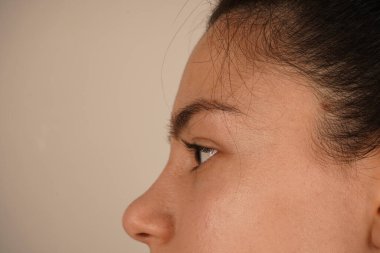 Kızın detaylı bir yan görüntüsü koyu saçlarını gösteriyor. Minimalist kompozisyon yüzünün hatlarını vurguluyor. Çekim zarafet ve gençlik cazibesi yayar.