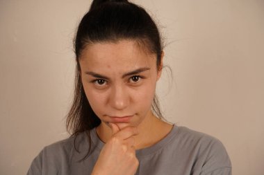 Çenesi elinde dinlenirken, genç kadın dalgın bir hava yayıyor. Rahat duruşu ve sakin tavırları bir anlık yansıma olduğunu gösteriyor. Bu poz düşünmeyi ve iç konsantrasyonu betimler.