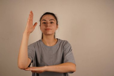 Bir öğrenci dirseği desteklenmiş bir şekilde elini kaldırır ve cevap vermeye hazır olduğunun sinyalini verir. Bu duruş, bağlılığı, dikkati ve katkıda bulunma arzusunu yansıtıyor. Öğrenme ortamında klasik bir jest.