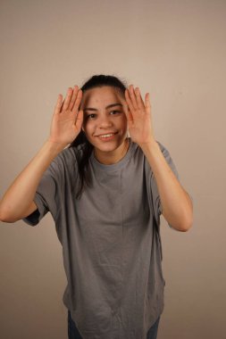 Avuç içleri yüzüne bastırılmış, nazikçe periferik görüşü engelliyor. Bu jest bir gizlilik ya da içgözlem hissi yaratır. İlgi çekici bir merak ve koruma karışımı ekliyor.