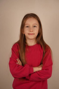 Kızıl saçlı bir kız kollarını kavuşturup kendine güveni ve zarafeti yayıyor. Onun sakin duruşu onun güçlü varlığının altını çiziyor. Parlak ayar çarpıcı özelliklerini çerçeveler.