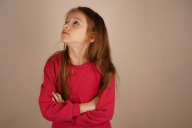 Kızıl saçlı bir kız kollarını kavuşturup kendine güveni ve zarafeti yayıyor. Onun sakin duruşu onun güçlü varlığının altını çiziyor. Parlak ayar çarpıcı özelliklerini çerçeveler.