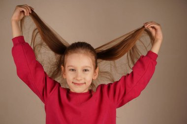 At kuyruklu kız iki eliyle kızıl saçlarının tellerine dokunuyor. Yumuşak jesti saçlarının canlılığını ve dokusunu vurguluyor. Bir anlık hayranlık.