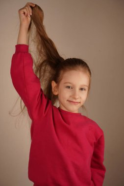 Kız doğal güzelliğini vurgulayarak at kuyruğundan çıkan kırmızı bir saç teline hafifçe dokunuyor. Parmakları ince ince tellerin arasında hareket ediyor, zengin renklerini ve pürüzsüz dokusunu takdir ediyor.
