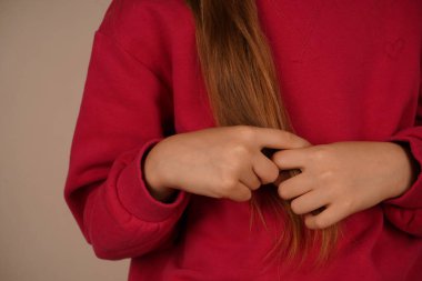 Genç bir kız doğal güzelliğini göstererek uzun kızıl saçlarına hafifçe dokunur. Onun zarif duruşu parlak rengi vurguluyor. Bu an, onun hayranlığını ve güvenini uyandırıyor.