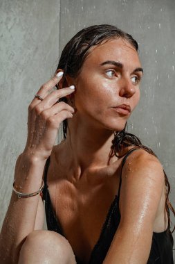 Yüzüklerin parlaklığı su damlacıklarıyla çok güzel zıtlaşıyor. Özgüven ve entelektüelliğin bir birleşimi. Su saç ve vücudun üzerinden akar. Duşta cesede dokunan eller.