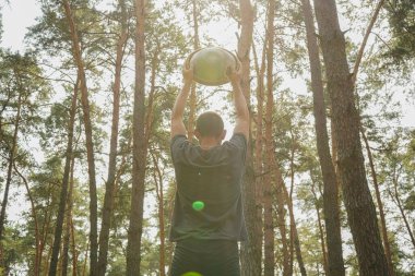 Ormanda başının üstünde bir pervane tutan bir adam, ağaçların arasından akan güneş ışığının tadını çıkarıyor. Doğada bir müzikal farkındalık anı