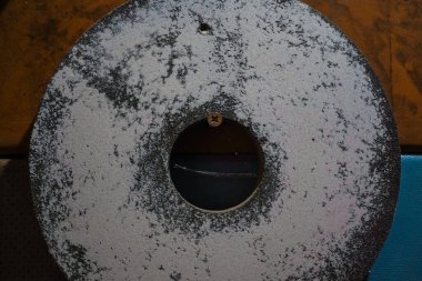 A circular sharpening stone used for grinding metal tools. Its coarse surface ensures precise shaping and durability. A vital tool in metalworking and craftsmanship