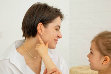 Anne kızıyla vakit geçiriyor. Kız annesinin boynundaki kolyeye şakayla dokunuyor. Bir çocuğu oyunlar ve konuşmalarla büyütmek