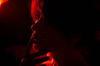 Eldivenli parmaklarını dudaklarının yanında tutan bir kadın yüzünün yakın plan görüntüsü.