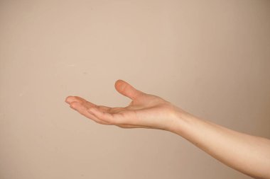 Avuç içinin yukarı dönük olduğu tek bir elin yakın çekimi, hafif bir arkaplana doğru çekiliyor. Jest açıklığı ve kavranabilirliği simgeliyor. Duruşun basitliği, temizliği ve minimalizmi vurgular.