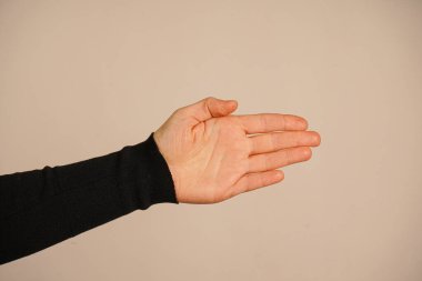 Nazikçe uzatılmış bir avuç içi, yardım ya da diyalog teklifini simgeler. Bağlantı ve destek temalarını somutlaştırır. Temiz zemin, jestlere odaklanmamızı sağlıyor. Merhaba demek için.