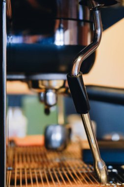 Kahve makinesinin detaylı bir görüntüsü, cilalanmış krom kaplamasını ve buhar çubuklarını ortaya çıkarır. Bu da her kafe kahve yapma sürecinin kalbini gözler önüne serer.