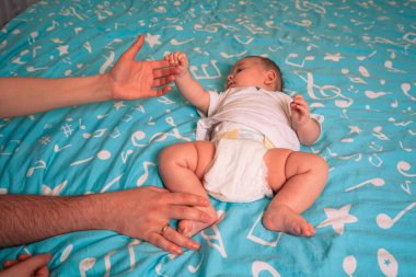 Ebeveyn parmağı, bebeğin küçük eli tarafından nazikçe tutulur. Güven ve sevginin sonsuz bir görüntüsü.