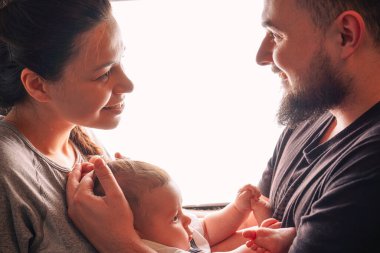 Anne, babasının koluna nazikçe yerleştirilir. İkisi de oğullarına sevgi ve neşe dolu ifadelerle bakar.