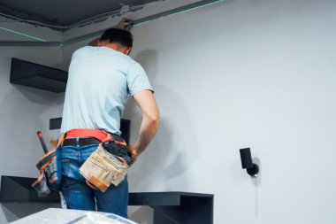 İşine odaklanan zanaatkar, yapıyı dikkatli ölçümler ve sağlam aletlerle duvara sabitliyor.