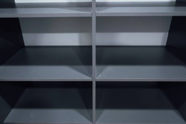 A gray cabinet with a variety of gray drawers for storing accessories. The wardrobe has white wooden shelves