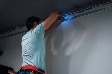 Tamircinin biri beton tavanı deliyor. Etkili bir şekilde çalışırken dengesini koruyor.