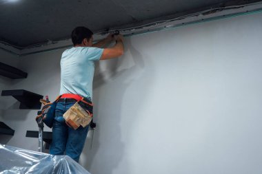 Adam matkabı başının üstünde tutuyor. Belinde alet kemeri var.