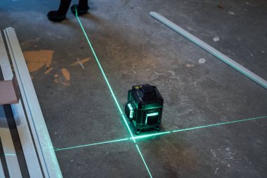 Çıplak zemin boyunca uzanan iki üst üste binen yeşil lazer hattı, inşaat işleri için parlak ve hassas bir hizalama oluşturuyor.