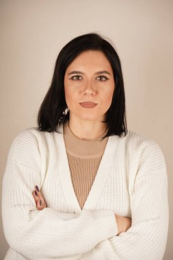 Beyaz kazak giyen, kollarını önünde kavuşturmuş güzel Avrupalı bir kadın.