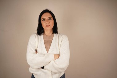 Genç iş kadını kollarını göğsüne dayayıp katlıyor. Kameraya bakan dost canlısı bir kadın.