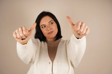 Kadın elini baş parmakları aşağıda tutuyor, hoşnutsuzluğunu açıkça ifade ediyor. Onun ciddi ifadesi hoşlanmama mesajını güçlendiriyor. Sahne güçlü bir olumsuz tepkiyi çağrıştırıyor.