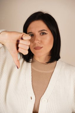 Çelişkili duyguların görsel temsili. Bir fotoğrafta hoşlanıp hoşlanmamak gibi. Düşünceli kadın, ikiliği sembolize ederek baş parmağını kaldırır ve baş parmağını aşağı uzatır.