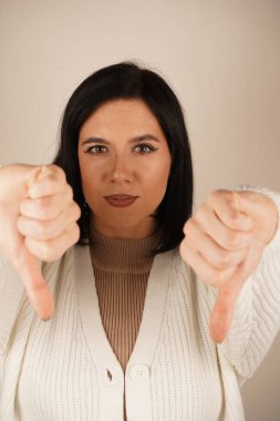 Onun odaklanmış ifadesi hoşlanmama duygusunu vurgular. Hoşnutsuzluk ve reddedilme mesajı. Ciddi bir kadın çifte baş parmak işareti gösteriyor, hayal kırıklığını ifade ediyor.