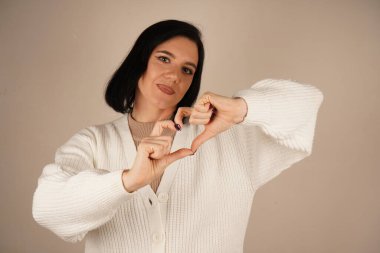 Onun sakin tavrı samimi bir anı yansıtıyor. Güzel bir aşk gösterisi. Sakince gülümseyen kadın ellerini bir kalbe dönüştürür. Bu da sevgi ve huzuru simgeler.