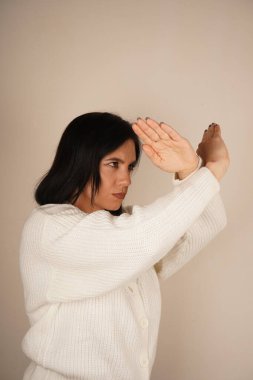 Jest kararlılık ve kararlılığı gösteriyor. Bir kadın kollarını önünde kavuşturur, yumruklarını sıkar, korunmaya hazır olduğunun sinyalini verir. Duruşu bir savunma ve güç hissi veriyor.