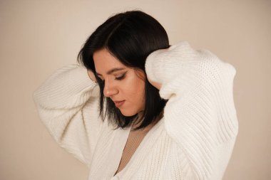 Elleri başının üstünde ve dirsekleri bükülmüş olarak poz vermesi bir rahatlama hissi veriyor. Duruş sükuneti ve sükuneti gösteriyor. Bu bir rahatlama ve rahatlama jesti.