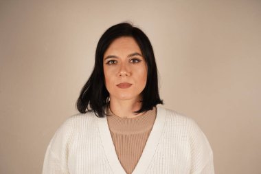 Açık arkaplanda gri tişörtlü genç bir kadının yakın plan portresi. Doğal görünüş, kızın genç yaşını vurgular. Resim siyah saçlı bir kadını gösteriyor.