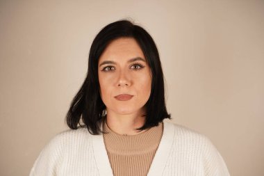 Açık arkaplanda gri tişörtlü genç bir kadının yakın plan portresi. Doğal görünüş, kızın genç yaşını vurgular. Resim siyah saçlı bir kadını gösteriyor.